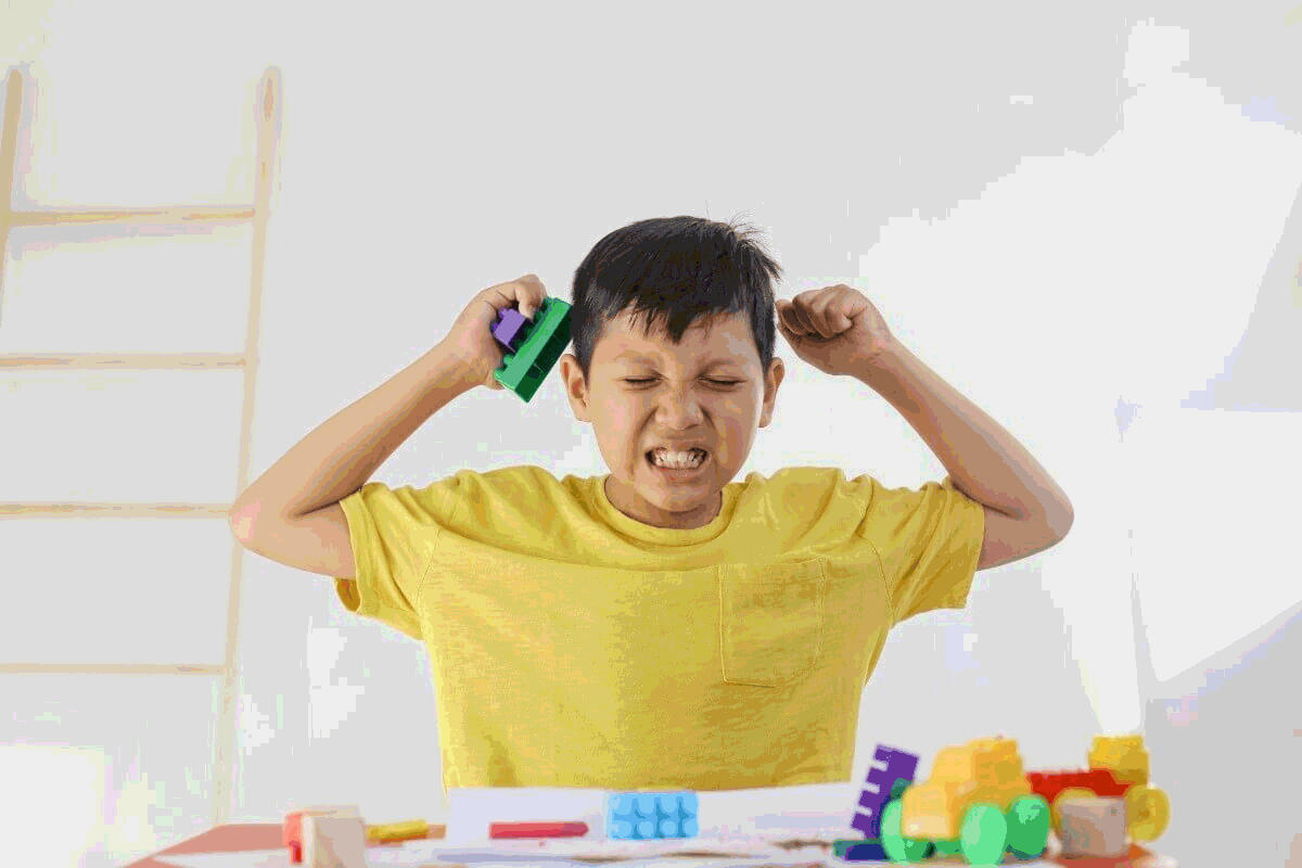 Foto de menino zangado, segurando blocos de montar. “Meu filho não quer estudar” é uma reclamação bastante comum entre as mães