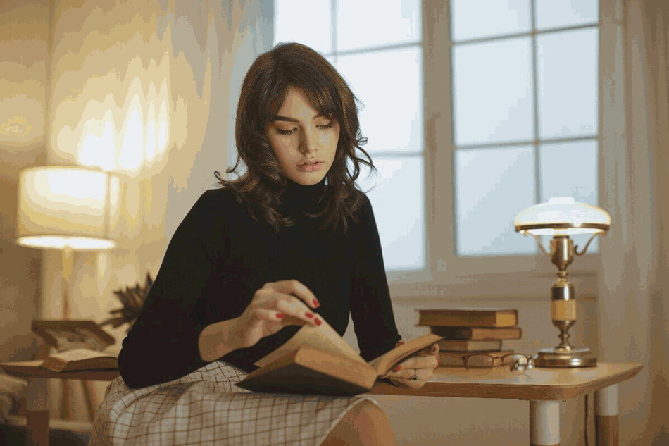 Foto de mulher em casa lendo livro. Dicas de leitura são ótimas para quem quer desenvolver esse hábito.