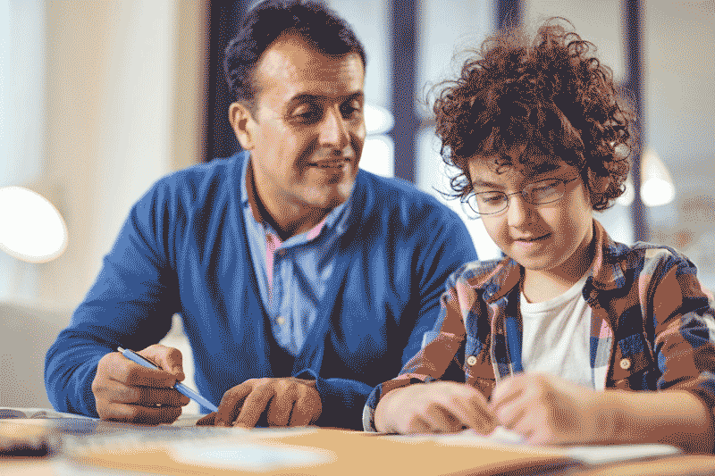 Foto de menino e pai estudando em casa. A família é fundamental para retomar a aprendizagem da educação infantil na pandemia.