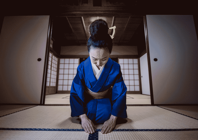Foto de mulher de quimono, ajoelhada em um tatame. A tradição faz parte da cultura japonesa.