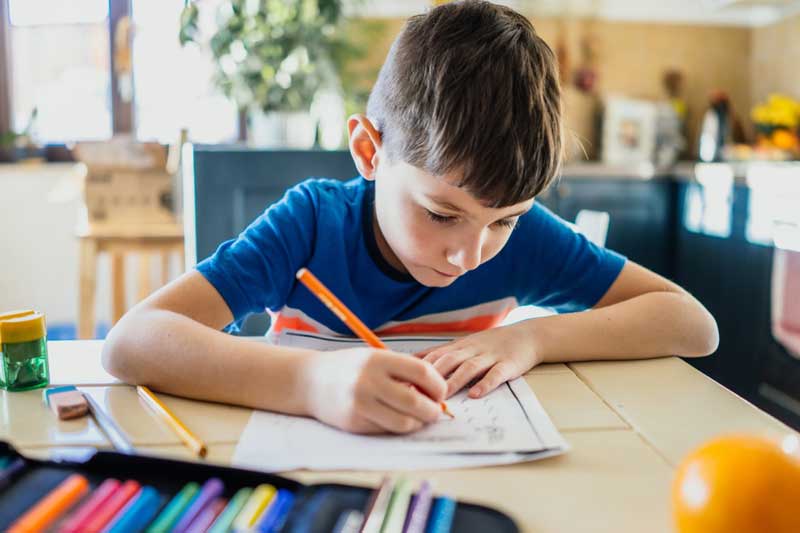 Foto de menino fazendo a lição de casa.