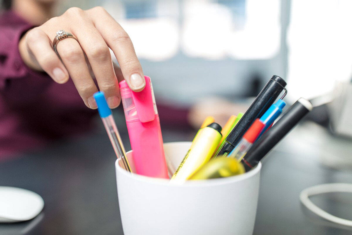Foto de canetas coloridas em um pote. Uma mão feminina pega uma delas. As dicas para focar nos estudos mais simples sempre funcionam.