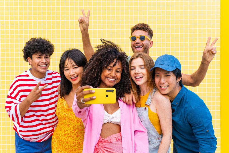 Foto de grupo de jovens amigos sorridentes fazendo uma selfie. A gíria em inglês para uma turma assim é squad ou crew.