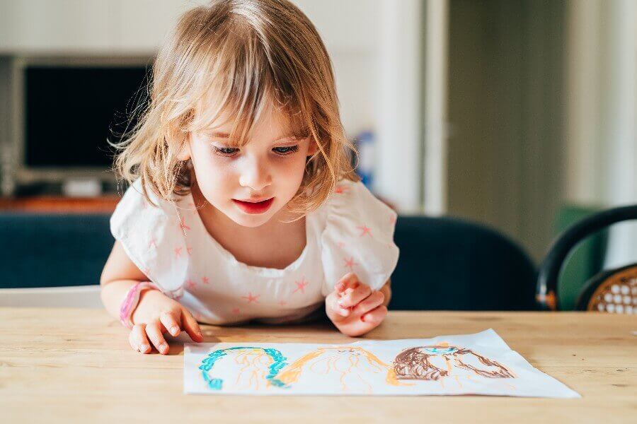 Foto de menina desenhando. A forma de desenhar está ligada às fases do desenvolvimento infantil.