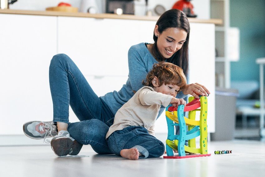 "Foto de jovem mãe e filho brincando com blocos. Conhecer as fases do desenvolvimento infantil ajuda as famílias e escolas a saber como estimular melhor as crianças."