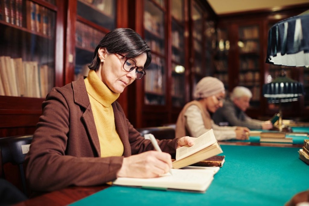 Foto de uma mulher adulta estudando em uma biblioteca.