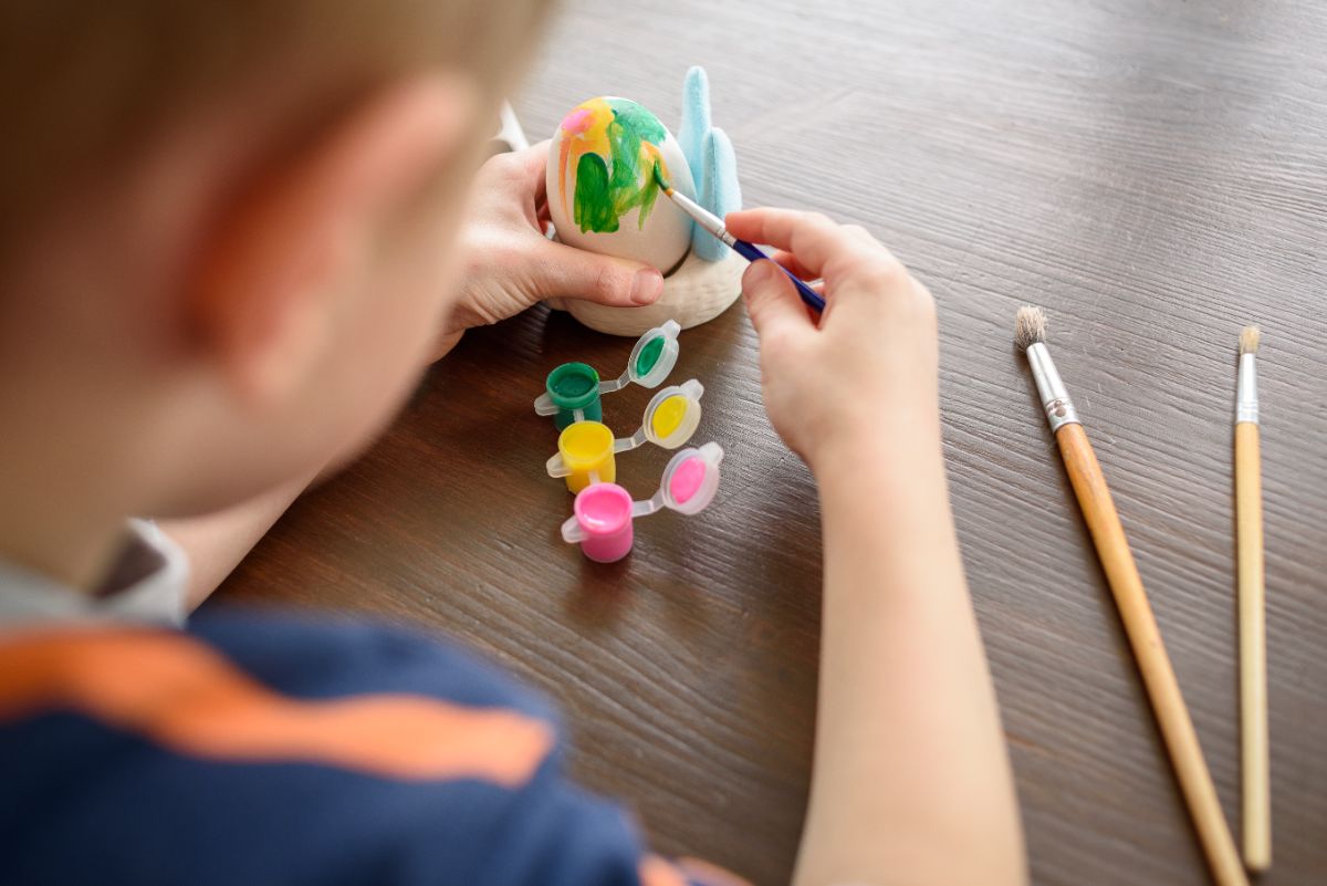 Criança pintando ovos para uma atividade de Páscoa.