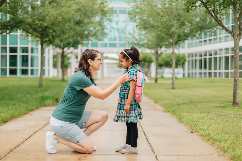 Mãe se despedindo da filha no primeiro dia de escola.