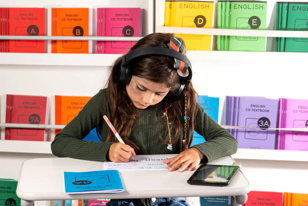 Menina com fones de ouvindo exercitando o seu inglês.