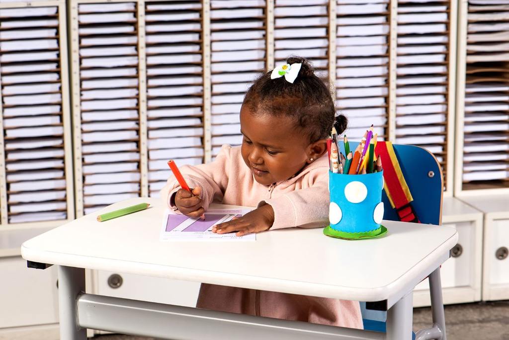 criança negra concentrada em resolver exercícios usando lápis e papel.