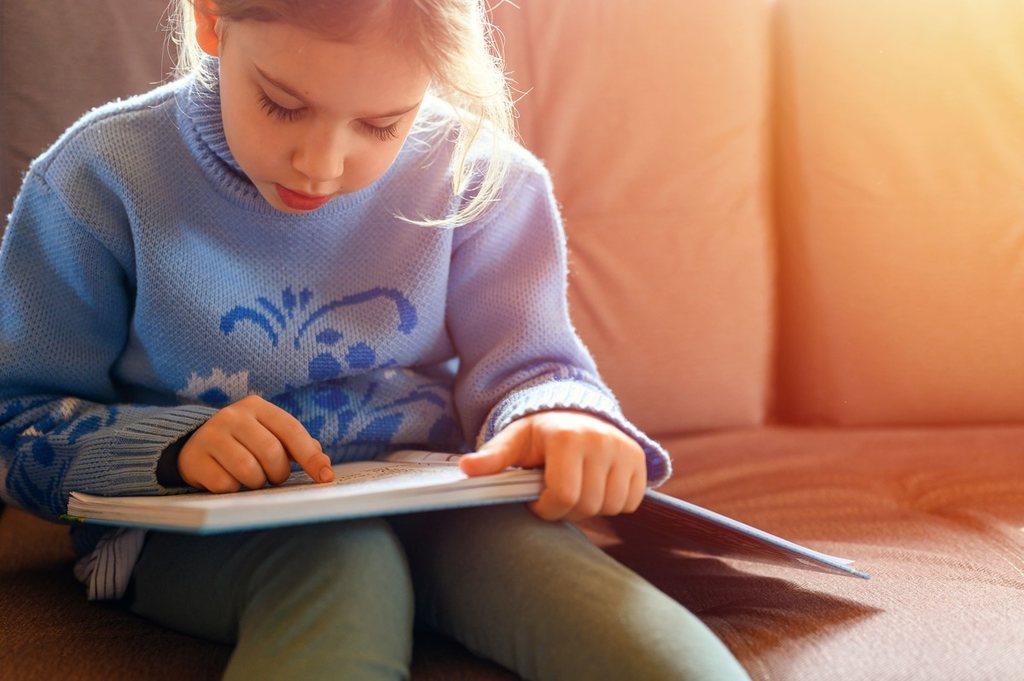 Menina dedicada lendo um livro.