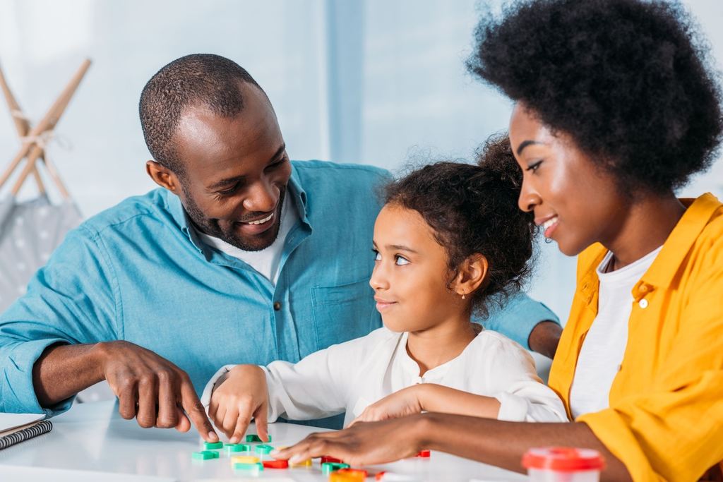 Menina aprendendo regras matemáticas com os pais.