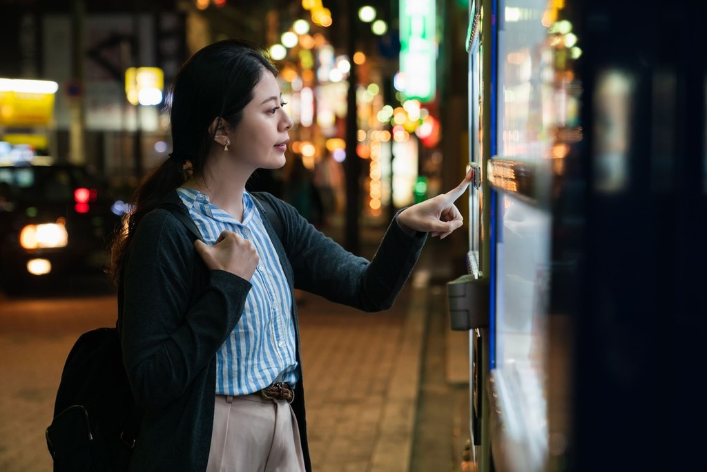 Mulher japonesa escolhendo seu pedido em uma máquina de vendas automática.