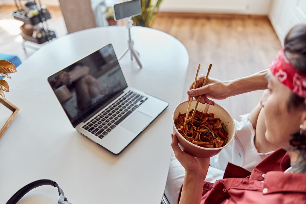 Jovem assistindo filmes japoneses e comendo yakissoba.