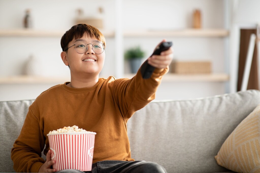 Jovem segurando um balde de pipoca e assistindo filmes japoneses.