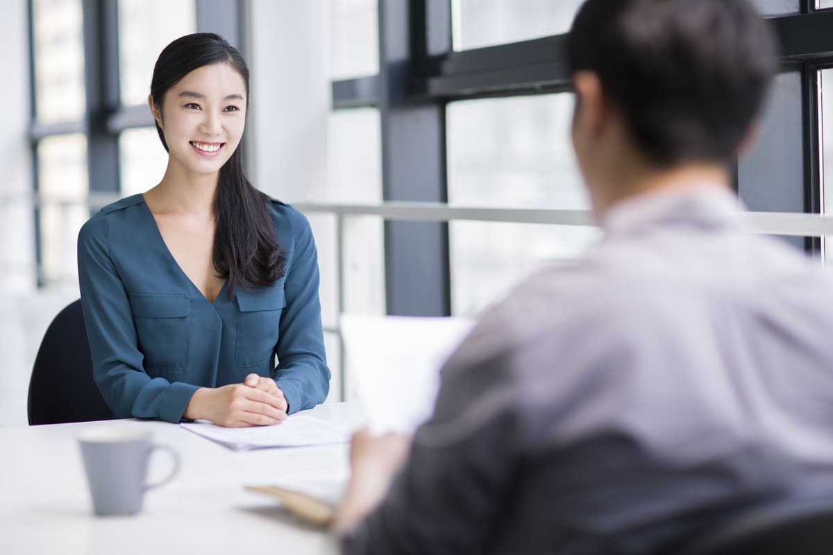 Jovem sorrindo em uma entrevista de emprego.