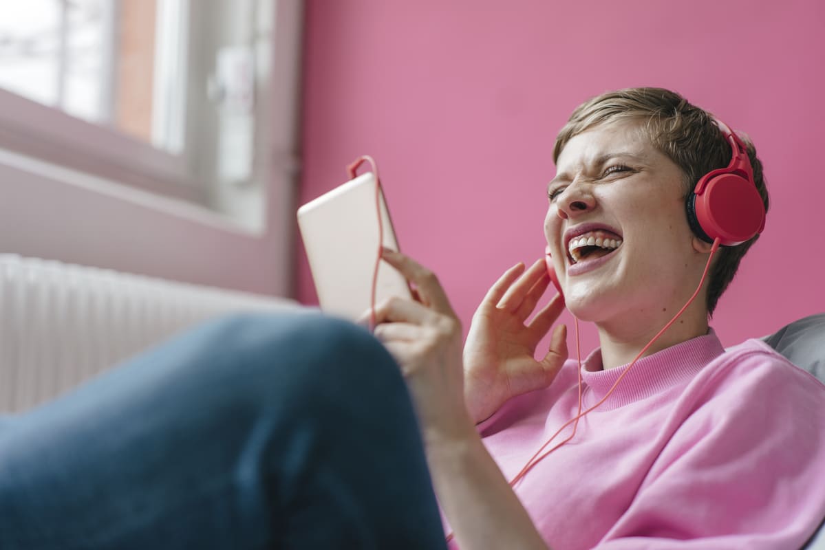 Mulher com celular e fones de ouvido ouvindo música.