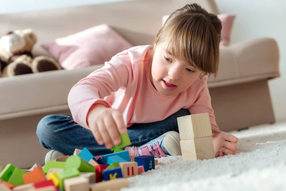 Criança brincando com cubos de brinquedo.