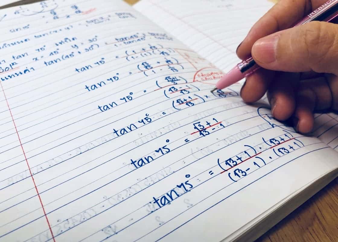 Mão de pessoa fazendo lição de casa de matemática.