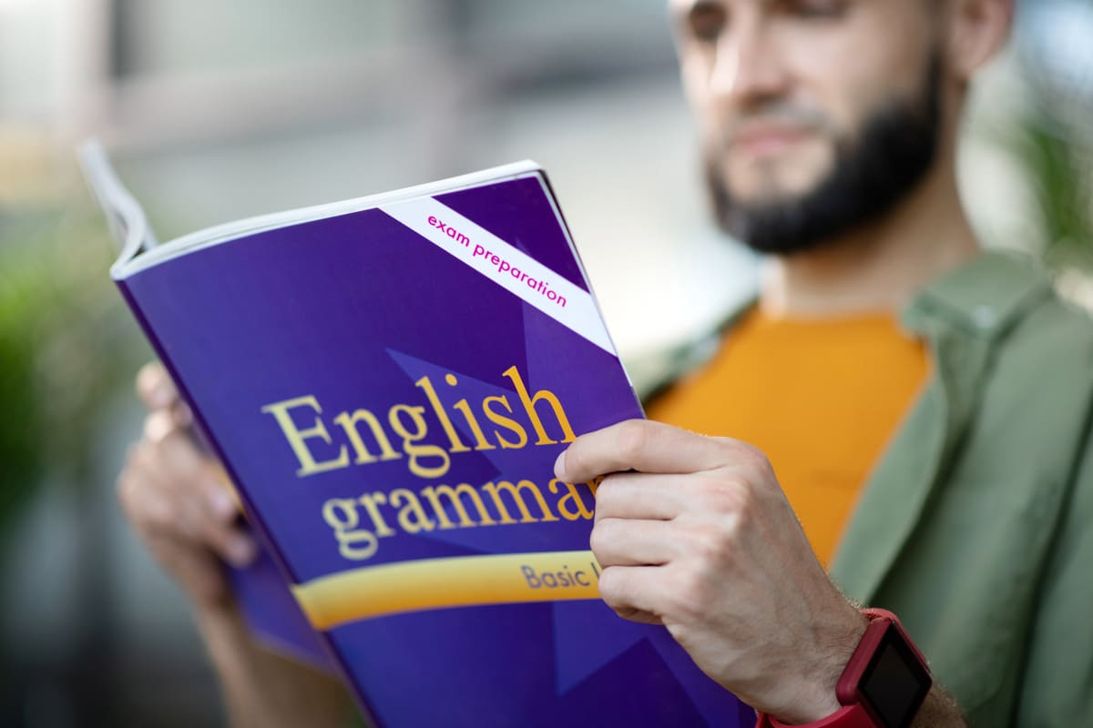 Homem lendo gramática em inglês.