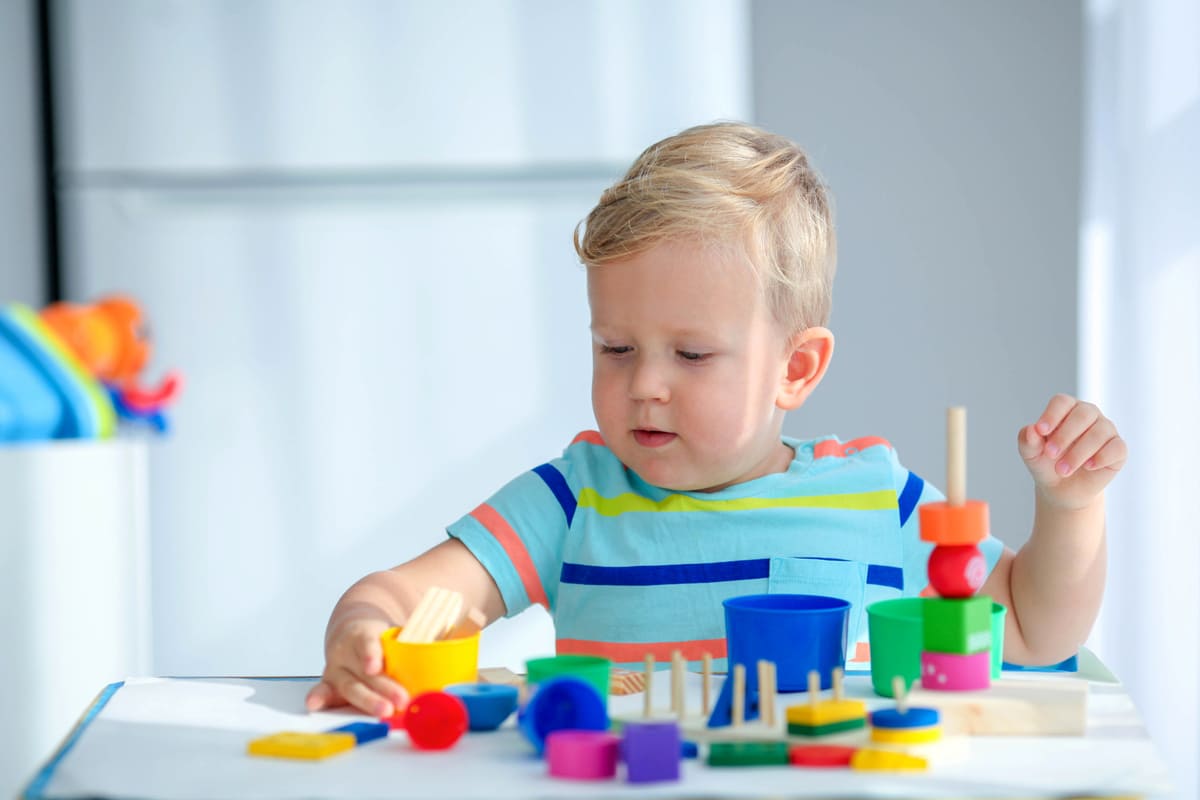 Menino brincando com blocos educacionais coloridos.