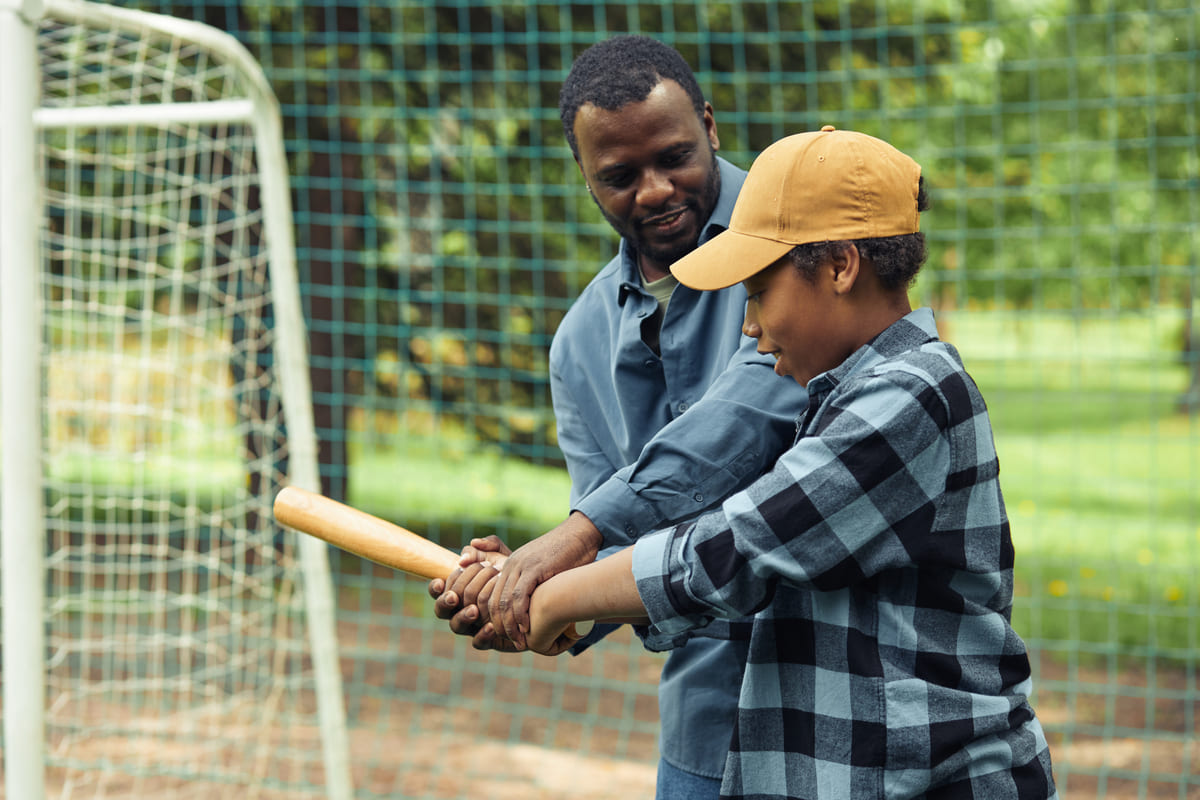 Pai ensinando seu filho a jogar beisebol.