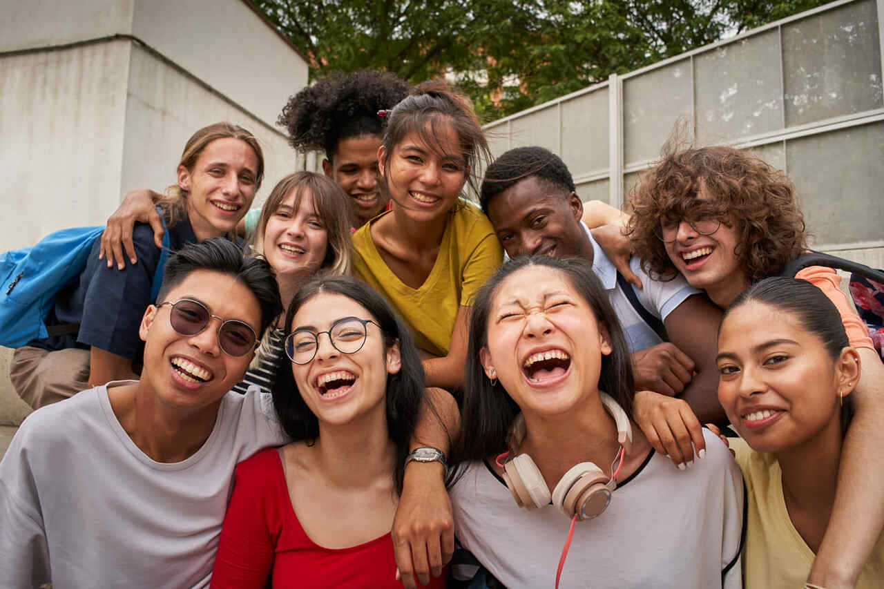 Selfie de um grupo de estudantes olhando para a câmera rindo.