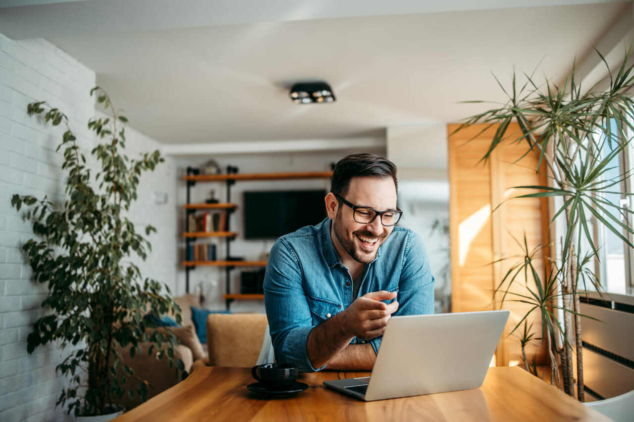 Homem rindo enquanto usa o computador.