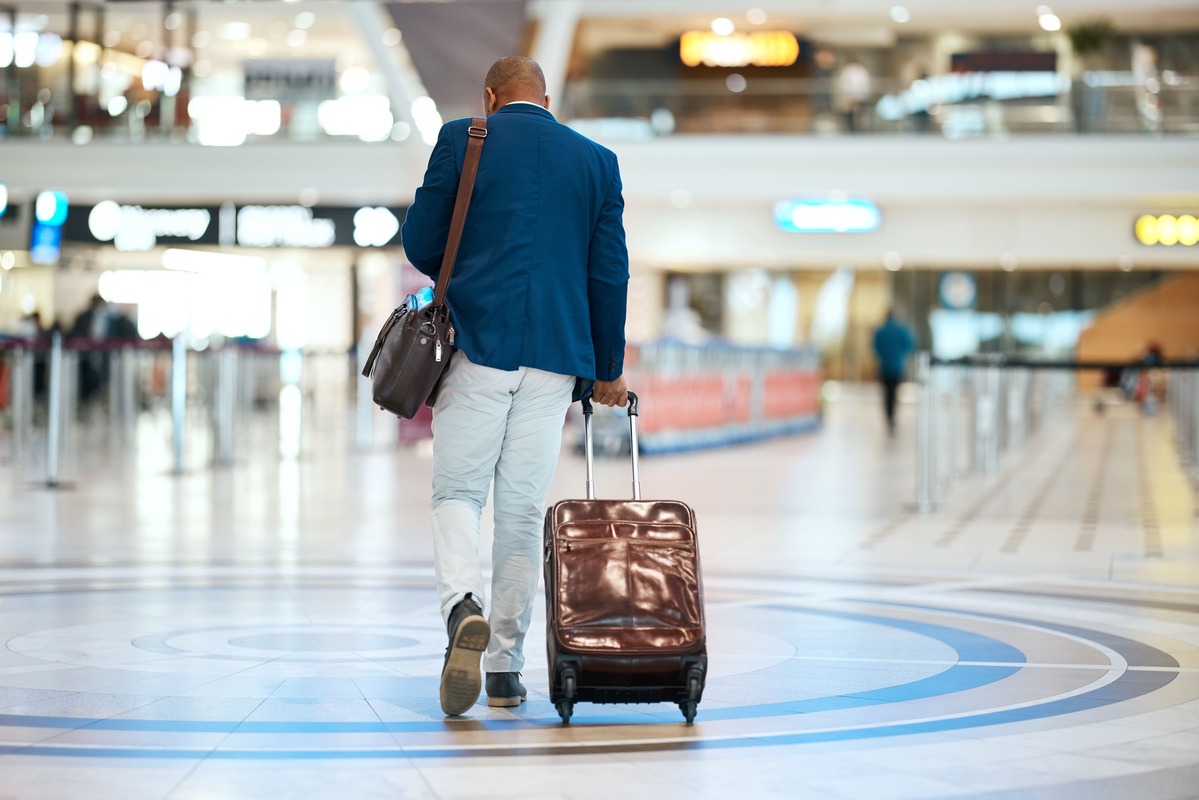 Homem vestido como executivo com mala no aeroporto.