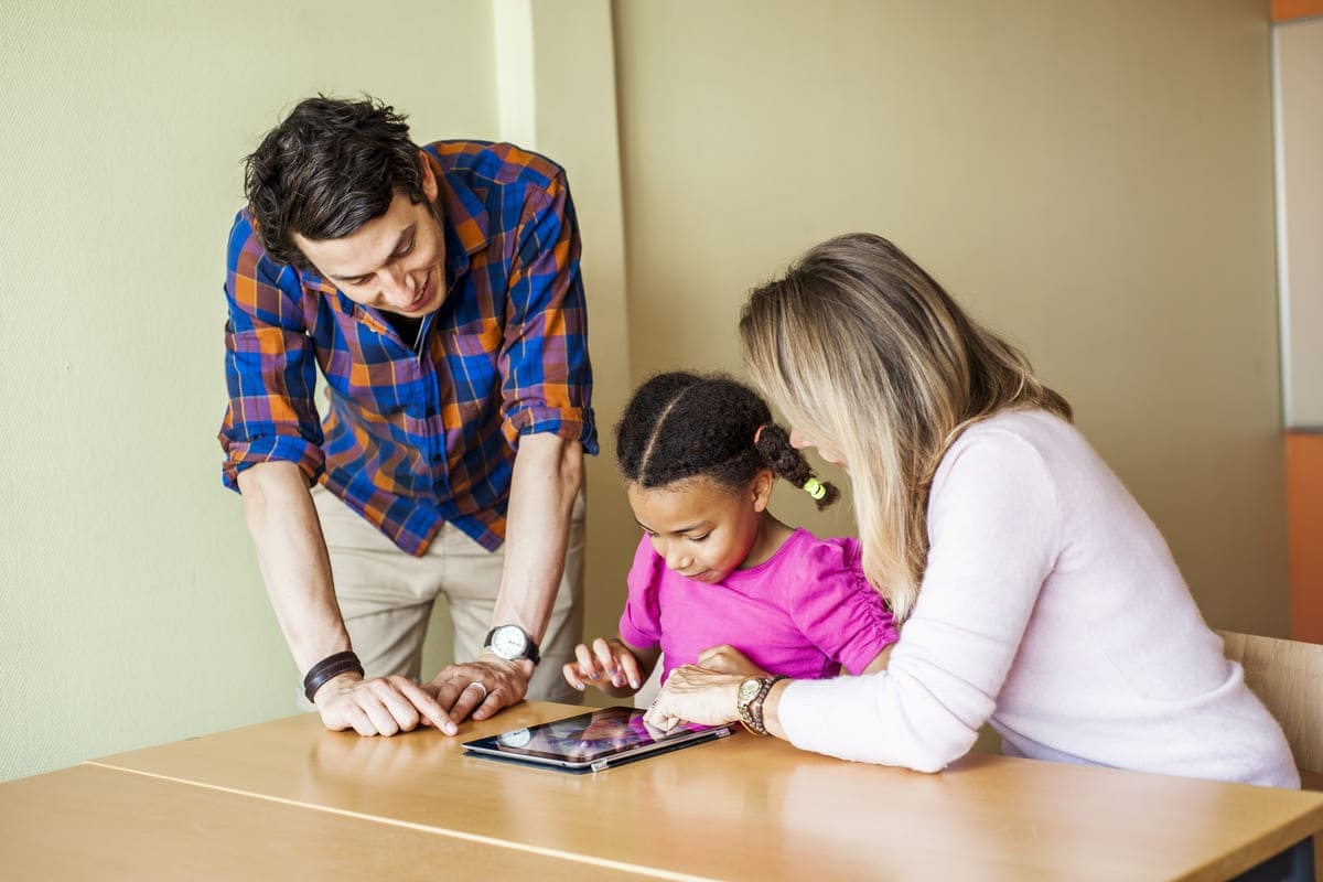 Adultos e menina estudando com tablet.