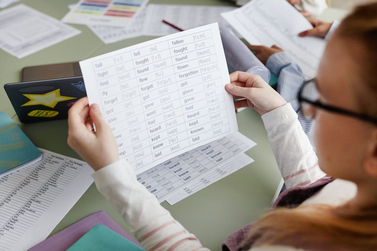 Menina aprendendo verbos irregulares em inglês.