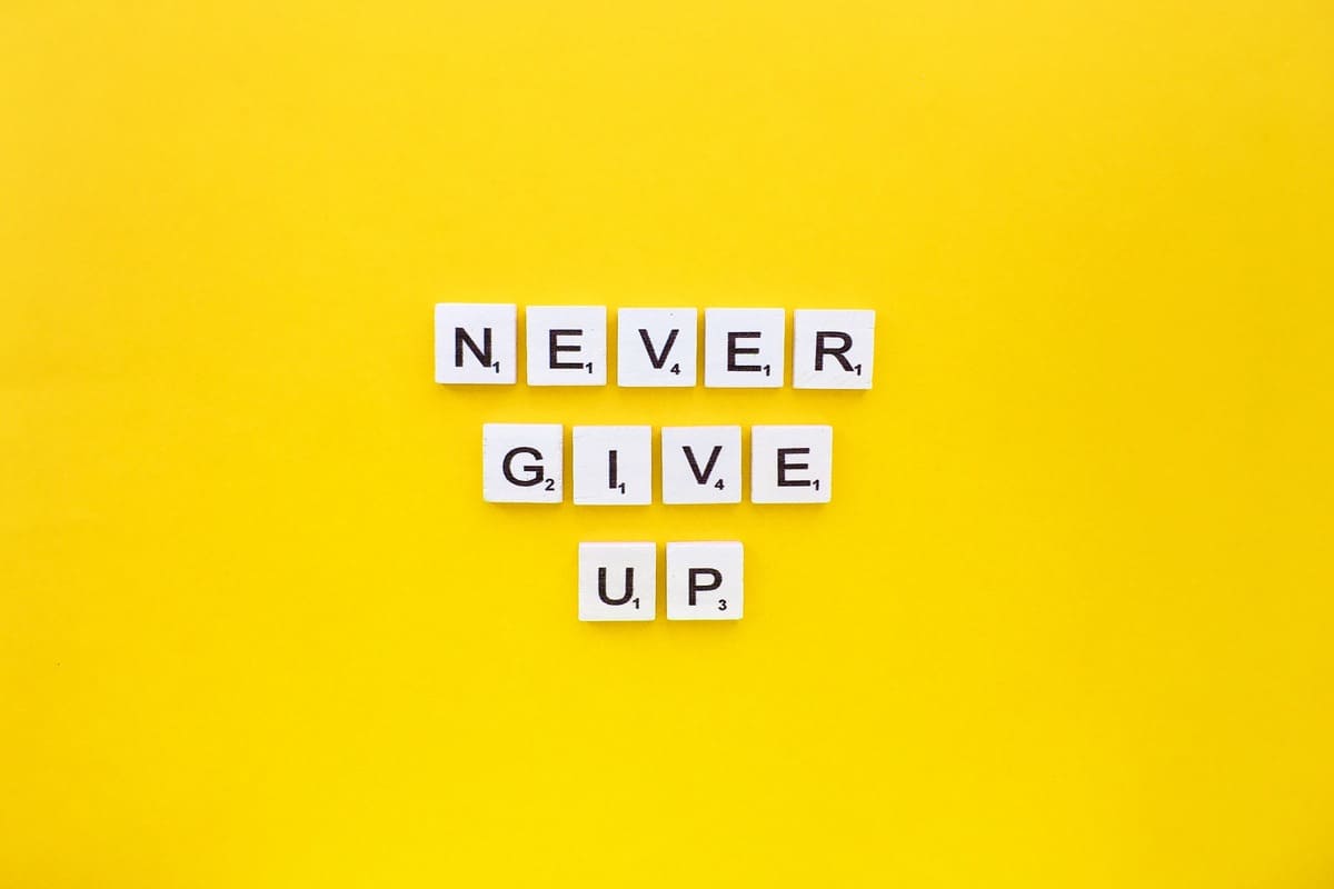 NEVER GIVE UP escrito em fundo amarelo. 