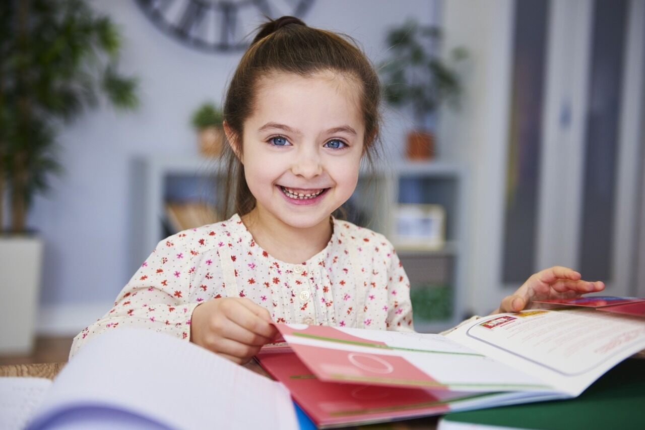 Criança sorridente estudando em casa.