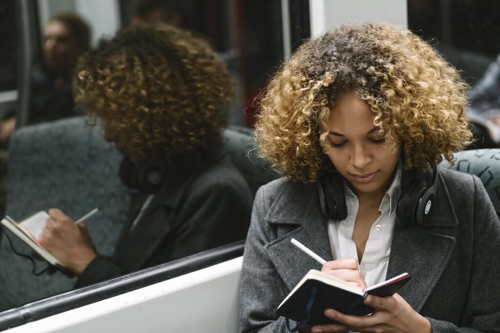 Mulher tomando notas em um metrô vendo como pensar em inglês