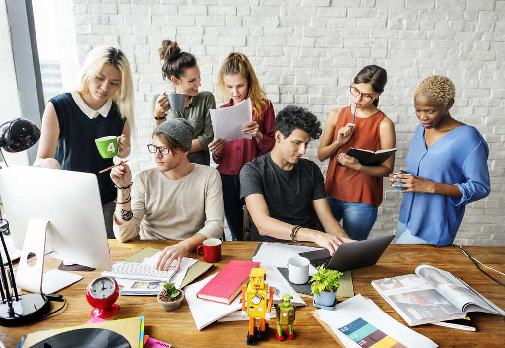 Equipe de trabalho reunida discutindo sobre nomes de reuniões corporativas em inglês