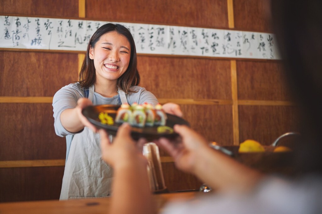 atendente de restaurante representando como se diz obrigado em japonês