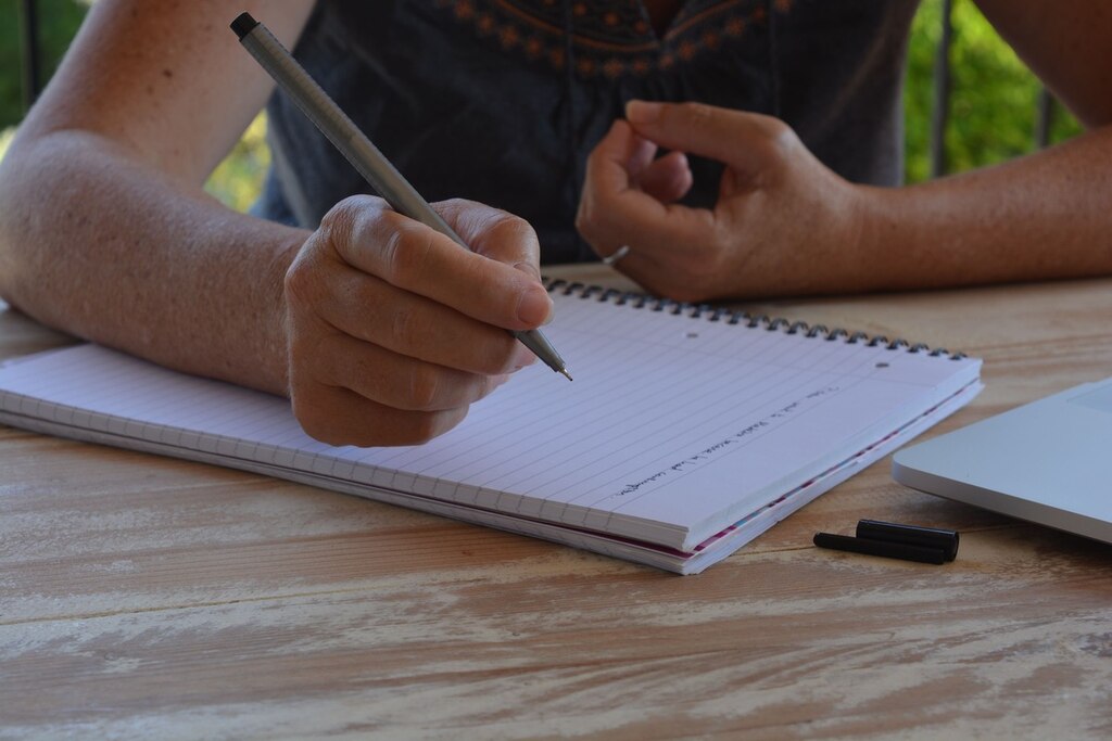 pessoa escrevendo em caderno sobre os termos onde ou aonde
