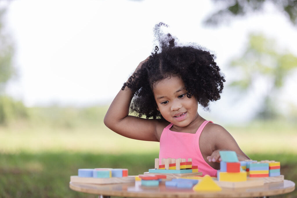 menina brincando com peças em mesa representando a autonomia infantil