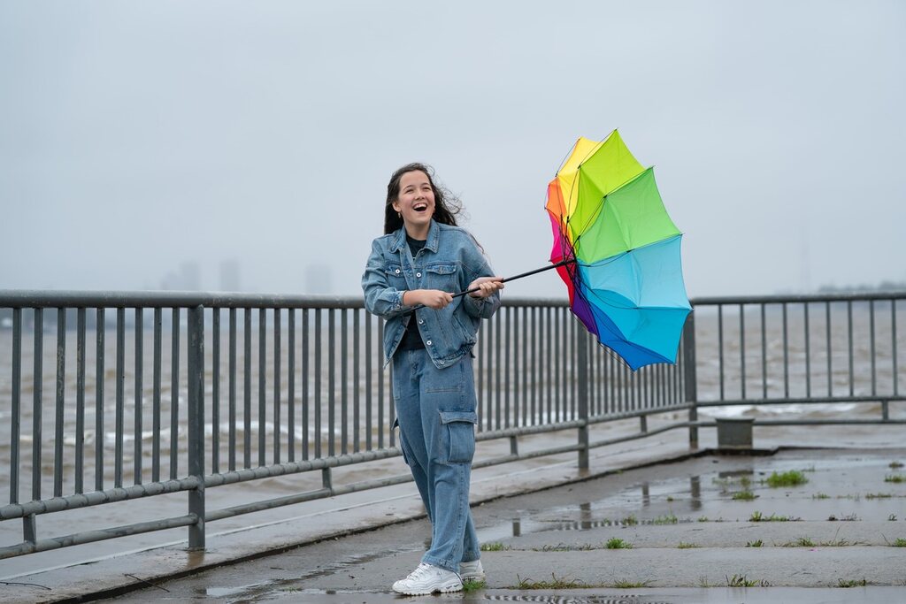 Menina com guarda-chuva em um dia chuvoso e ventoso que representa o frio em inglês