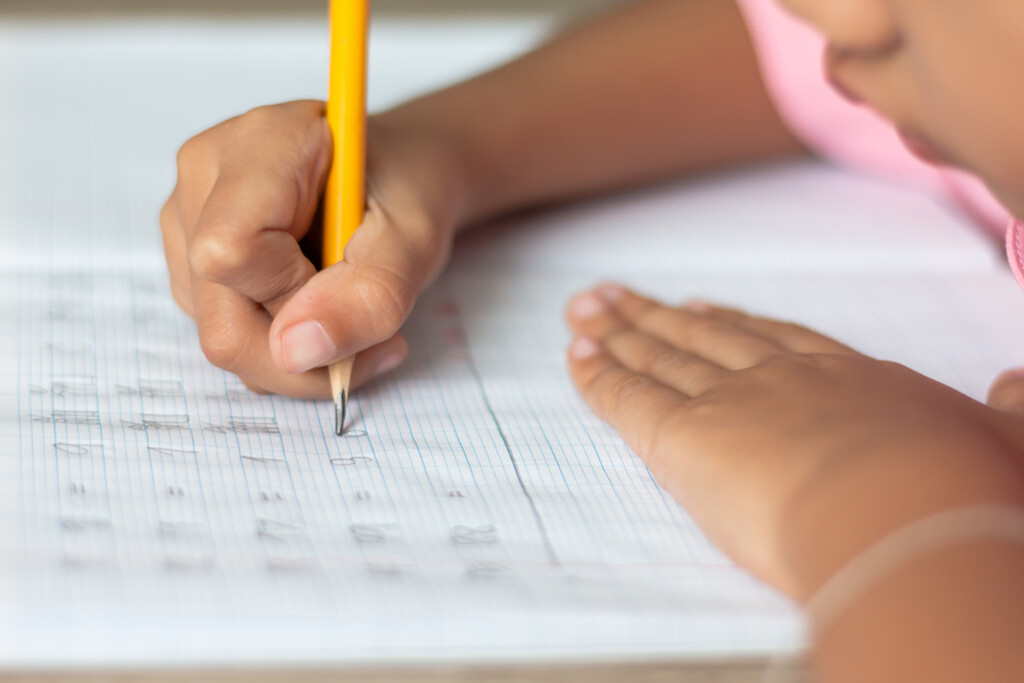 criança escrevendo em caderno representando a alfabetização