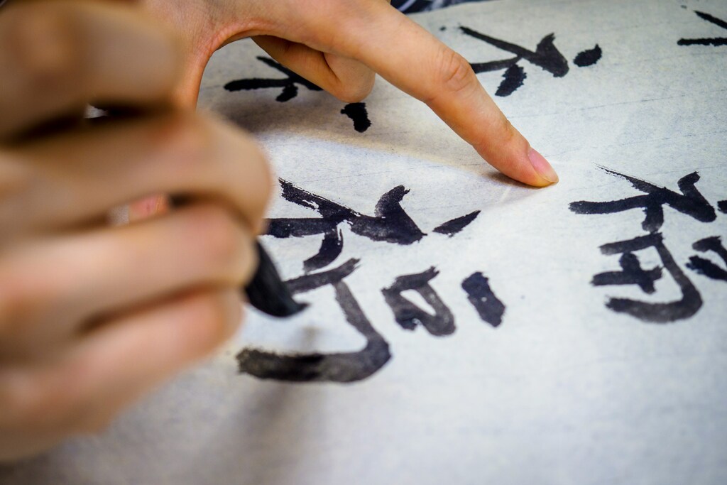pessoa escrevendo caracteres japoneses representando como aprender japonês