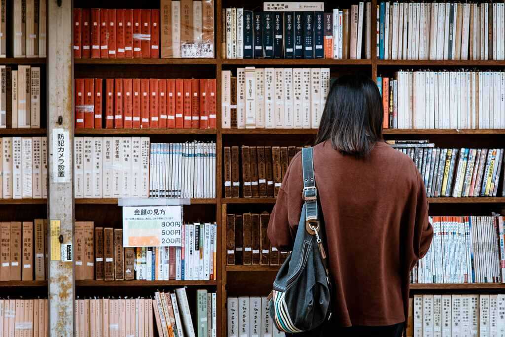 estudante em biblioteca buscando livros para aprender os números em japonês