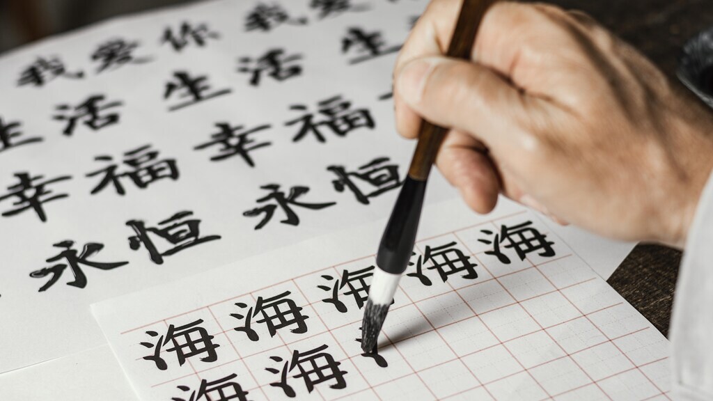 pessoa escrevendo caracteres em Kanji com tinta