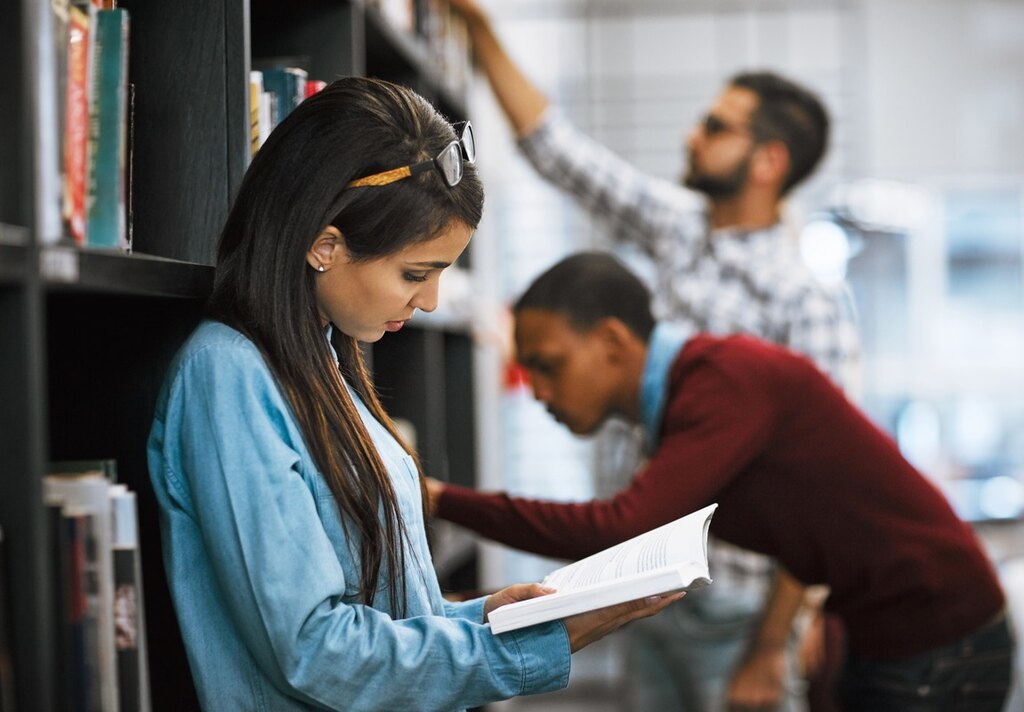 Aluna lendo na biblioteca para aprender a fazer redação em inglês