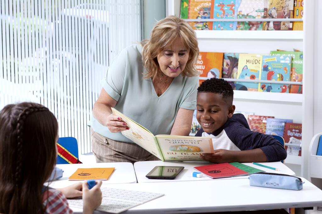 professora auxiliando aluno com tarefa da rotina da franquia do Kumon
