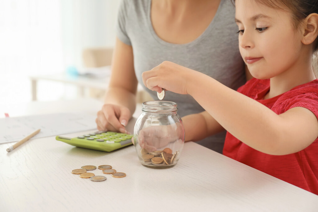 criança colocando moedas em pote depois de aprender cálculo mental