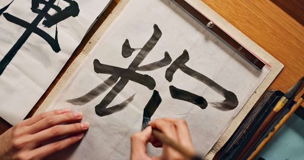 pessoa escrevendo kanji, representando o kun’yomi e on’yomi