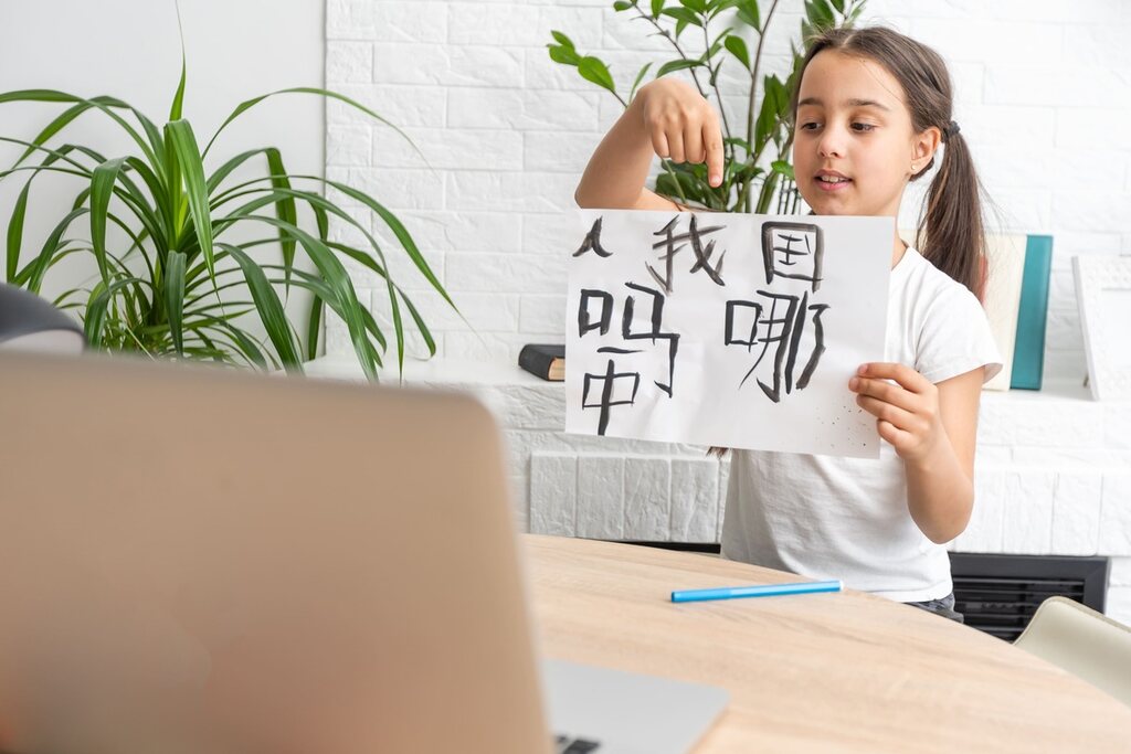 Garotinha com kanjis escritos em papel, depois de aprender sobre kun’yomi e on’yomi