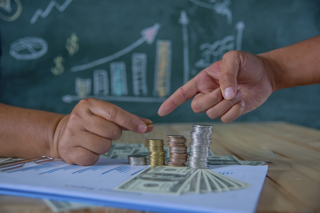 mãos empilhando moedas representando a matemática financeira