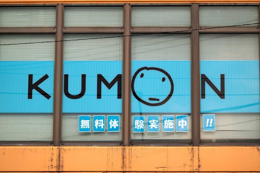 Parede com logo do Kumon, seguido de kanjis japoneses.